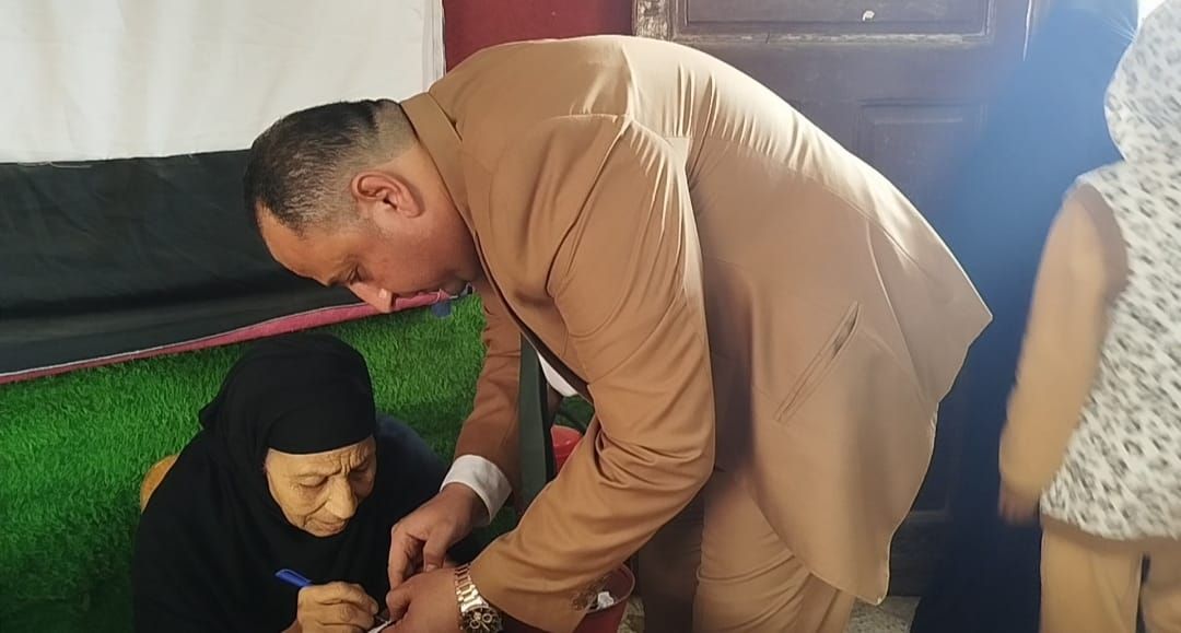 رئيس لجنة سيلا الابتدائية بالفيوم يساعد مسنّة على الإدلاء بصوتها